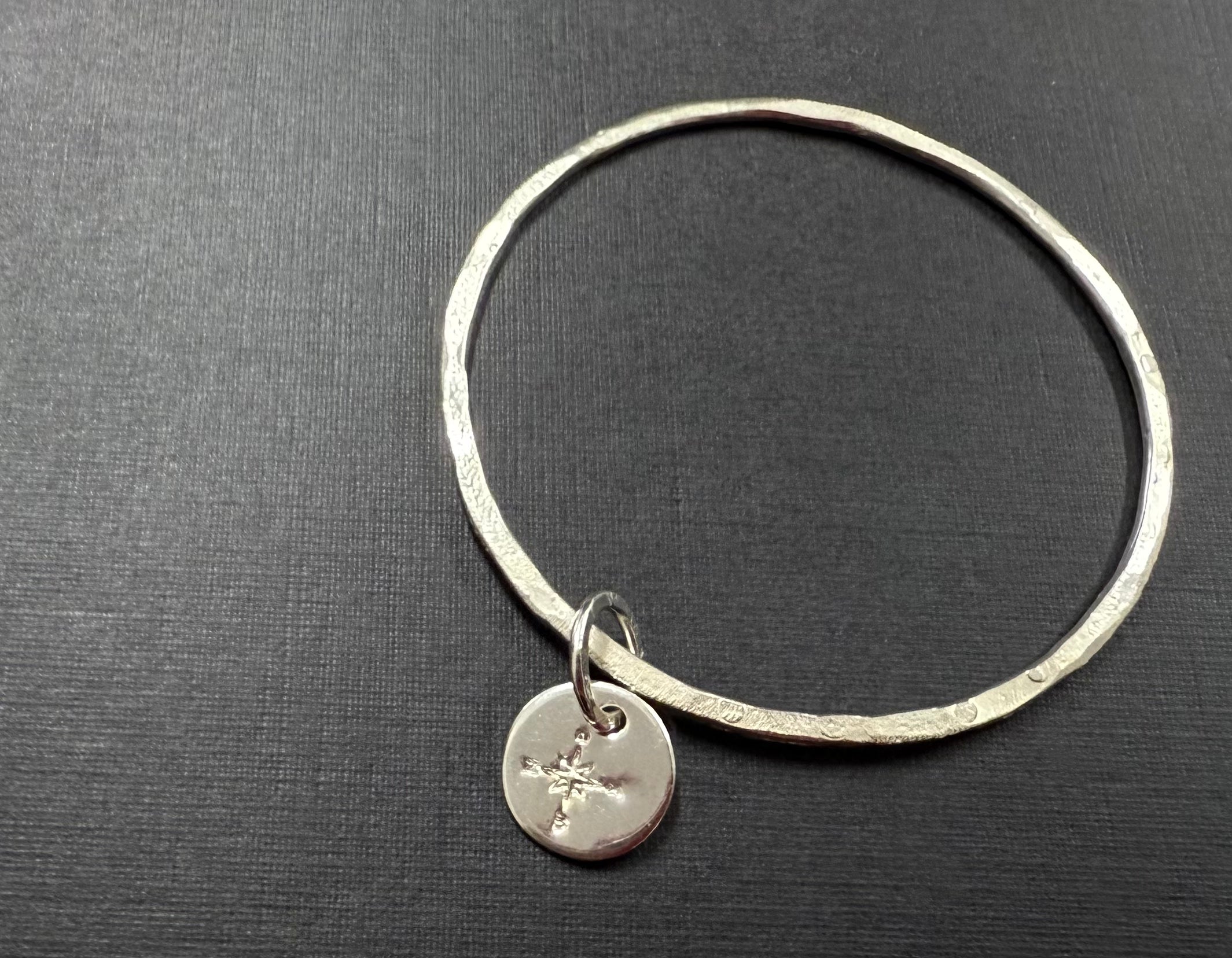 Thin silver bangle with stamped disc