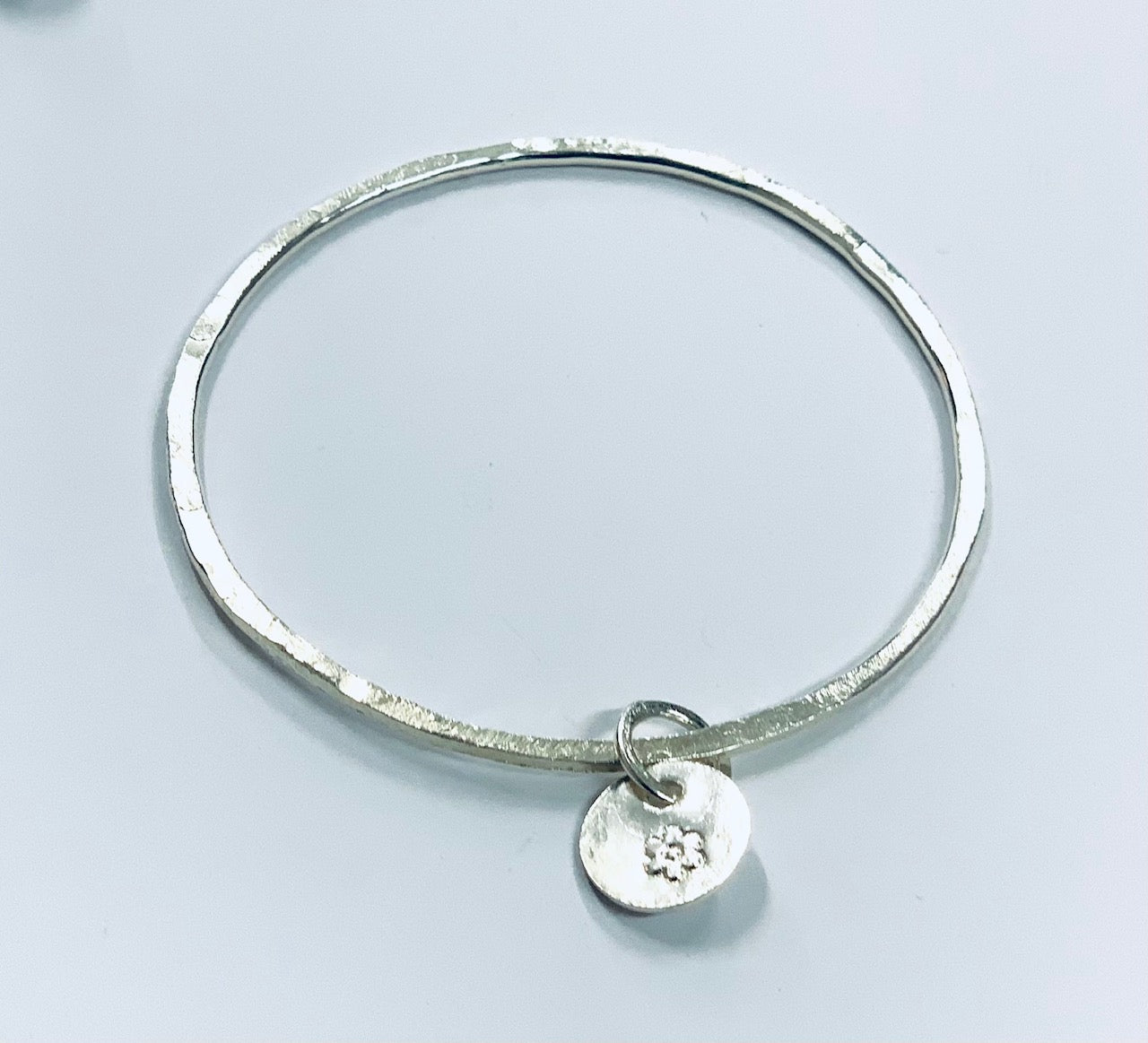 Thin silver bangle with round charm